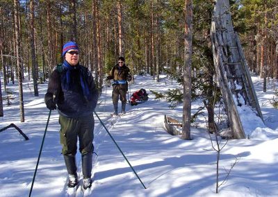 Kaksi hiihtäjää lumisessa metsässä.