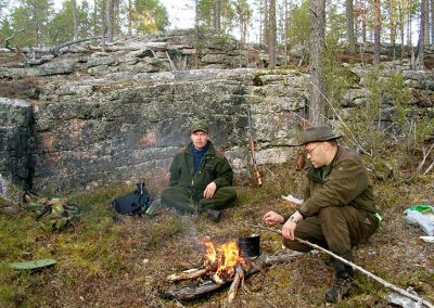Kaksi metsästäjää nuotiolla.