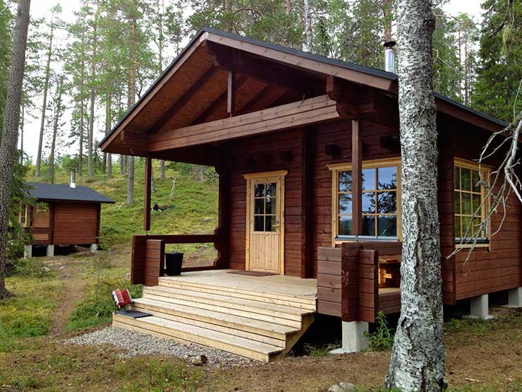 Hirsimökki kesämaisemassa.