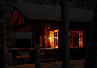 Mökin valaistut ikkunat pimenevässä maisemassa.